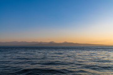 Beautiful golden sunset over the lake. The summer sun goes down behind the mountains.