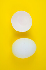 White egg and eggshell on the yellow background. Copy space. Minimalism, original and creative photo. Beautiful wallpaper. Easter holidays.