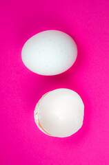 White egg and  eggshell on the pink background. Copy space. Minimalism, original and creative photo. Beautiful wallpaper. Easter holidays.