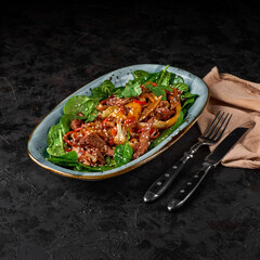 Asian beef salad with vegetables and nuts in a white bowl on a dark background. Asian food concept.