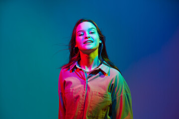 Smiling young modern stylish teen girl posing in colorful neon studio light. Woman beauty portrait with copy space