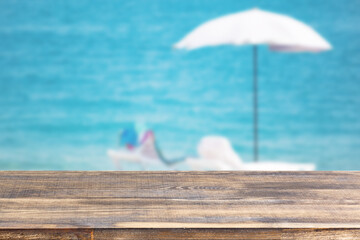 wood table top on blur beach umbrella on the sea background