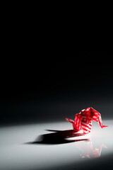 Beautiful back light scene of red origami elephant isolated on black background