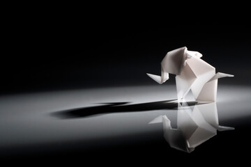 Beautiful back light scene of white origami elephant isolated on black background