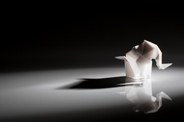 Beautiful back light scene of white origami elephant isolated on black background
