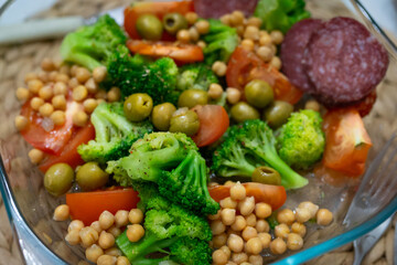 keto diet. Chickpeas, green broccoli, olives, tomatoes and salami slices in a plate close-up. Bio products