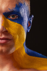 Ukraine fan. Soccer or football athlete with flag bodyart on face. Sport concept with copyspace.