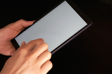 A person using his tablet with a white screen, ready to place any design on a black background