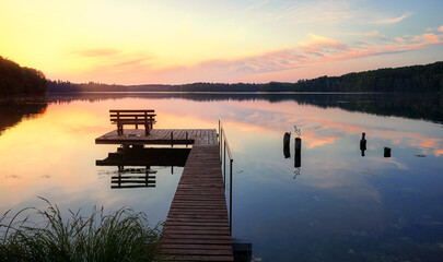 Fototapeta na wymiar Bench on a wooden pier at sunset, Lipie Lake in Dlugie Village, Poland