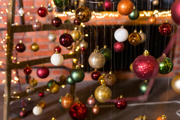 Fototapeta na wymiar A group of Christmas balls hanging on thin threads on blurred background. Happy new year theme. greeting card.Colorful Christmas small balls hang on ribbons