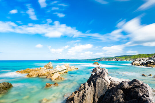 (Long exposure) Stunning view of a rocky coastline bathed by a turquoise, clear sea during a sunny, summer day, Rena Majore, Sardinia, Italy.