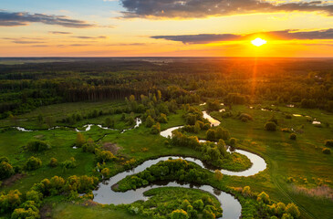 Beautiful aerial drone view of sunset over green fields and wild river