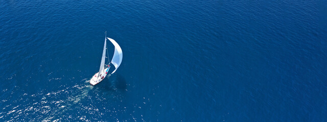 Aerial drone ultra wide panoramic photo of beautiful sail boat with white sails cruising deep blue...