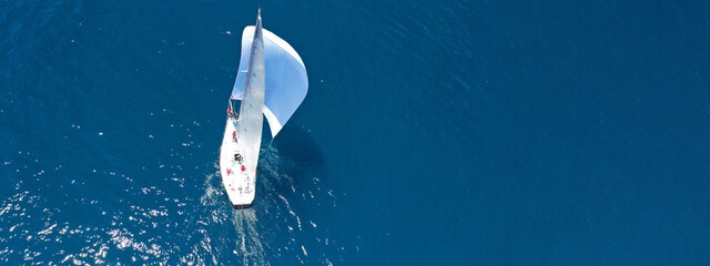 Aerial drone ultra wide panoramic photo of beautiful sail boat with white sails cruising deep blue...