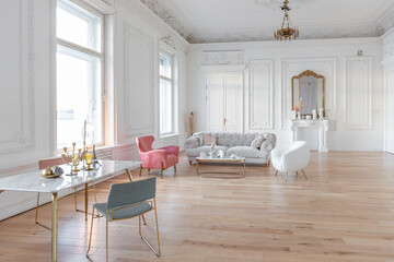 very light baroque style luxury interior of big sitting room. White walls decorated with awesome stucco. Royal style apartment with chic furniture with gold elements
