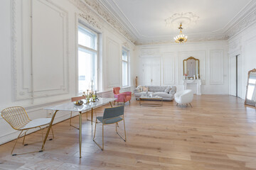 very light baroque style luxury interior of big sitting room. White walls decorated with awesome stucco. Royal style apartment with chic furniture with gold elements