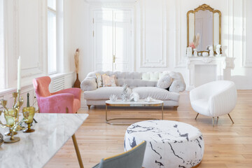 very light baroque style luxury interior of big sitting room. White walls decorated with awesome stucco. Royal style apartment with chic furniture with gold elements