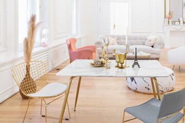 very light baroque style luxury interior of big sitting room. White walls decorated with awesome stucco. Royal style apartment with chic furniture with gold elements