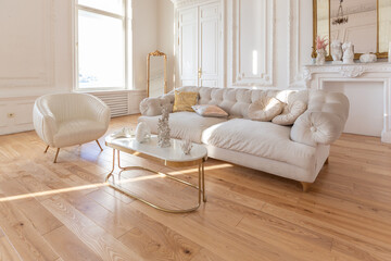 very light baroque style luxury interior of big sitting room. White walls decorated with awesome stucco. Royal style apartment with chic furniture with gold elements