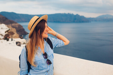 Tourist woman walking on Santorini island, Greece enjoying sea landscape. Traveler admires Caldera view in Oia
