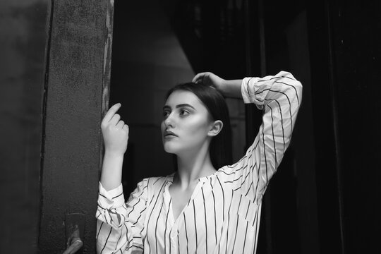 Black and white indoor portrait of a magnificent young woman wears striped white shirt