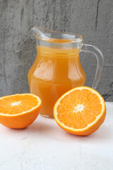 Fototapeta na wymiar concept of healthy food. Fresh orange juice in the glass jug and juicy fresh oranges on a neutral vertical background