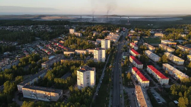 Flight over the evening city with a large mining enterprise. In the frame you can see the city center, and on the horizon a large enterprise with smoking chimneys