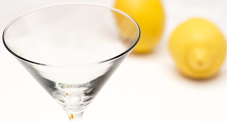 A clean martini glass with lemons in the background.