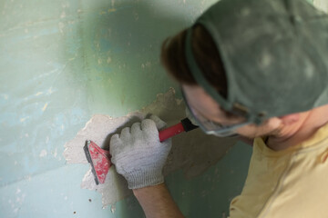 Caucasian man removing old paint with scraper tool. - obrazy, fototapety, plakaty