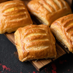 Homemade baking. Fresh Baked puff pastry buns or sweet breads on black table background. Square format. Soft focus. Close up shot.