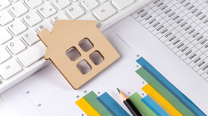 wooden house on the graph with keyboard. Economic chart. Real estate market.
