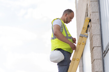 telecommunications technician climbing to the top of a ladder without a safety helmet on