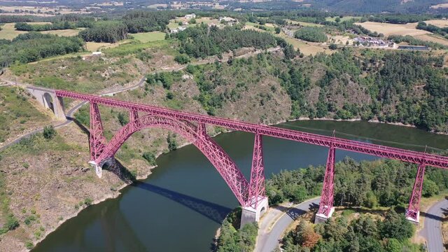 Scenic drone view of parabolic arched framework of railway bridge Viaduc de Garabit across river Truyere near Ruynes-en-Margeride in Auvergne, France