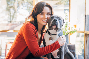 Smiling woman hugging her pet Pitbull dog