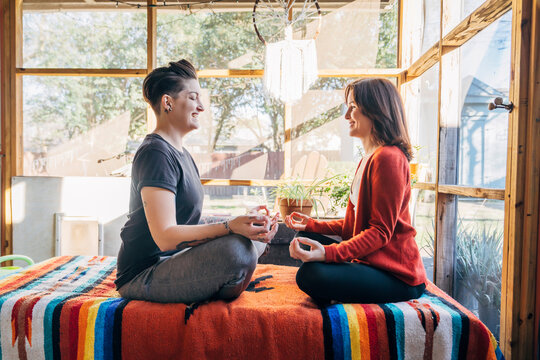 Women sitting and meditating facing each other and laughing