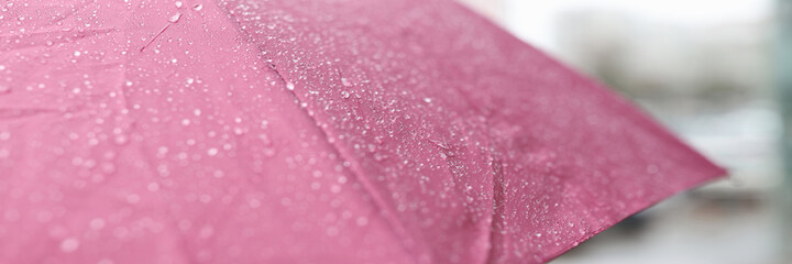 Raindrops running down wet pink umbrella closeup