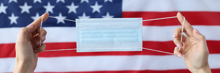 Hands holding protective medical mask in front of usa flag