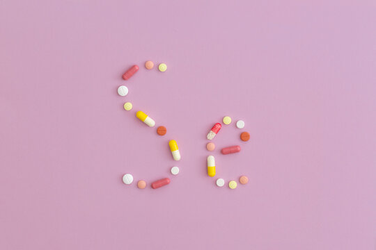 Selenium symbol made from pills on purple background. Top view with copy space. Flat lay.