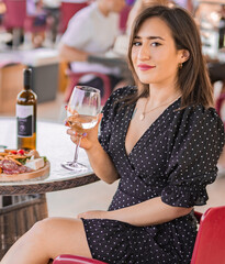 Italian woman in restaurant drinking white wine at sunset