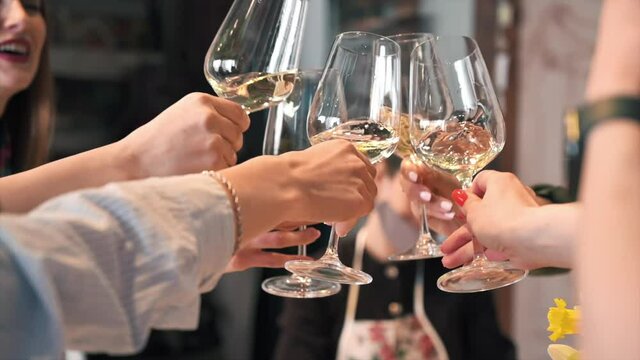 A group of young women clincking glasses of white wine