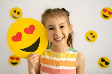 World emoji day. Anthropomorphic smile Face.  Birthday Party. Emotions. A little girl, smiling with...