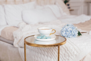 Romantic breakfast, cup of tea, macaroons and blue hydrangea flower on bedroom background