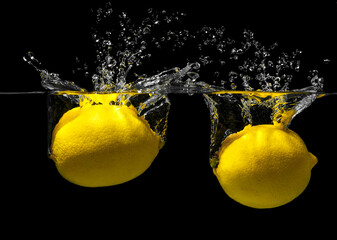 lemon sinking in water on a black background. Citrus with water splashes.