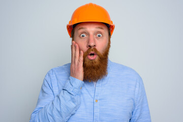 Isolated amazed architect with beard and orange helmet