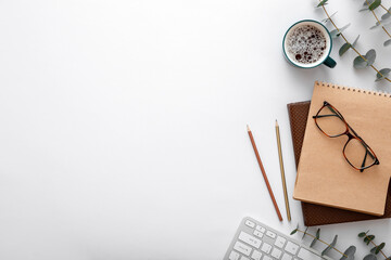 Glasses keyboard coffee cup notebook office supplies on desk top view. Modern desk workspace with...