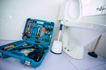 Close up photo of ceramic bowl toilet in domestic bathroom with a box of tools