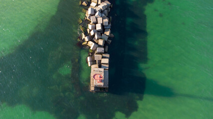 A breakwater made of white concrete cubes and a leading sign at the entrance to the port of Yuzhny. Odessa. Ukraine. Aerial view.