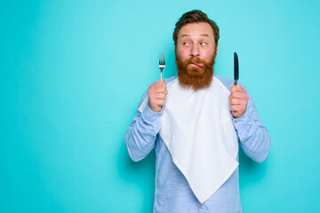 Man with tattoos is ready to eat with cutlery in hand