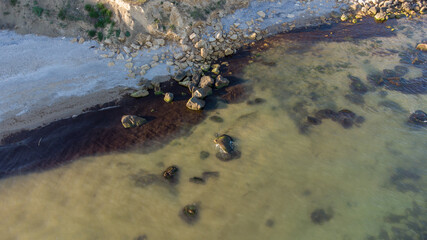 Aerial view of the stony seashore. Transparent water and stones in the water.