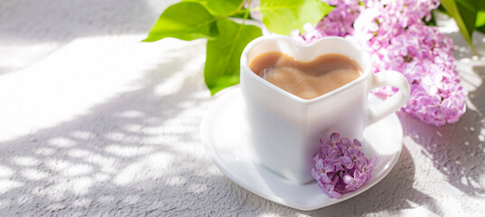 Obraz na płótnie Canvas Cappuccino coffee in a cup and a branch of lilac on a white background with shadows . A hot drink. relax. The concept of cafeteria advertising. Article about cappuccino. Making cappuccino. Lilac branc